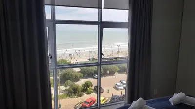 a bedroom window with a view of a beach at 604 St Tropez in Strand