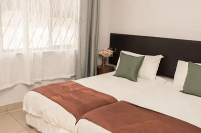 a bedroom with two beds with white sheets and green pillows at Mauya Guesthouse in Kuilsrivier