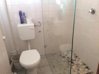 a bathroom with a toilet and a glass shower stall at Romilly Beach Apartment in Strand
