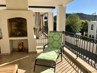 a green chair sitting on a balcony with a fireplace at Maison Malherbe in Franschhoek