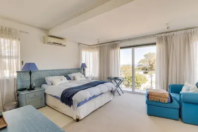 a bedroom with a bed and a blue chair at 42 on 4th in Hermanus
