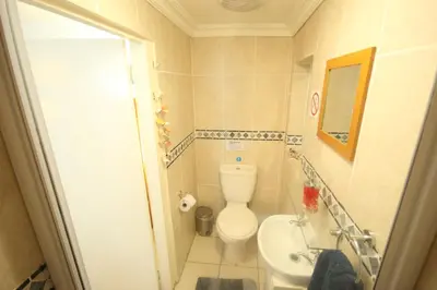 a small bathroom with a toilet and a sink at Saltycrax Backpackers and Surf Hostel in Bloubergstrand