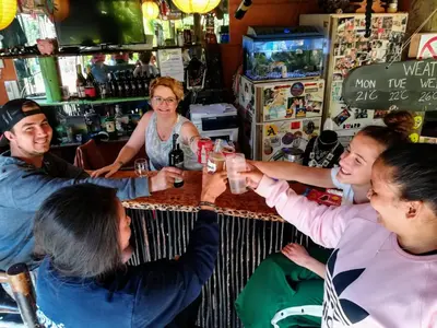 a group of people sitting around a table in a bar at Saltycrax Backpackers and Surf Hostel in Bloubergstrand