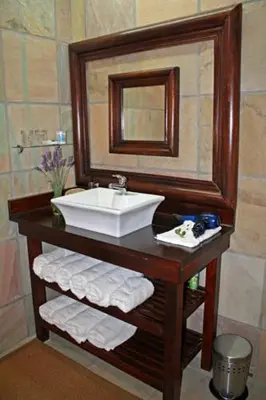 a bathroom with a sink and a mirror and towels at The Greens Guesthouse in Bellville