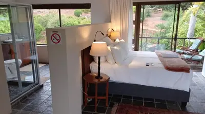 a bedroom with a bed with a lamp on a table at The Greens Guesthouse in Bellville
