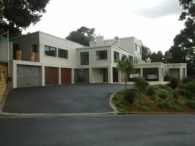 a large white house with a driveway at The Greens Guesthouse in Bellville