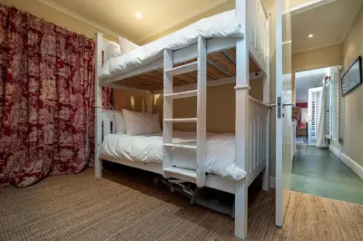 a bedroom with two bunk beds and a staircase at Cook's Cottage in Franschhoek