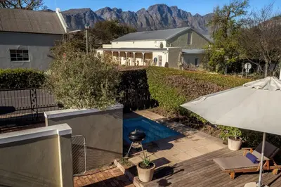 a house with a swimming pool and an umbrella at Cook's Cottage in Franschhoek