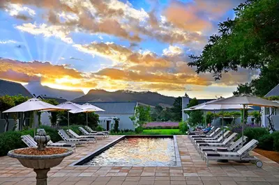 a pool with white lounge chairs and umbrellas at Lavender Farm Boutique Guest House in Franschhoek