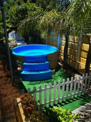 a pool with blue steps in a yard with a fence at a Vue Guesthouse in Somerset West