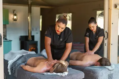 two women are getting a mans back massage on beds at AfriCamps at Doolhof Wine Estate in Wellington