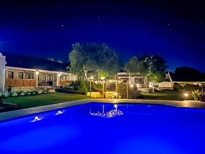 a large blue swimming pool in a yard at night at Lady Loch Country House in Wellington