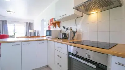 a kitchen with white cabinets and a stove top oven at Greenways Strand Golf Beach C3 in Strand