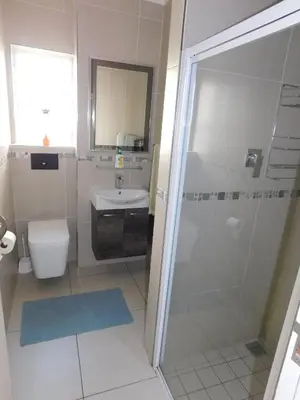 a bathroom with a shower and a toilet and a sink at Greenways Strand Golf Beach C3 in Strand