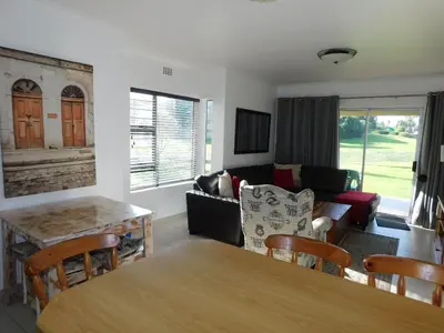 a living room with a table and a couch at Greenways Strand Golf Beach C3 in Strand