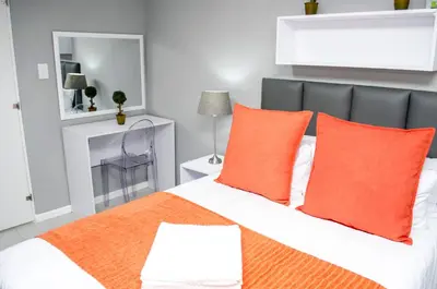 a bedroom with a bed with orange pillows at Cape Town Micro Apartments in Cape Town