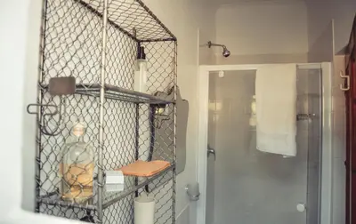 a bathroom with a shower and a shelf with a bottle at Hemel en Aarde cottages in Hermanus