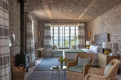 a bedroom with a bed and a living room with a fireplace at 7 Koppies in Franschhoek
