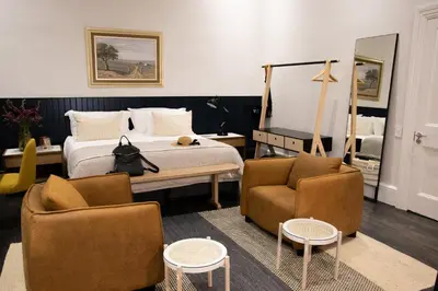 a bedroom with a bed and two chairs and a mirror at Heritage House in Stellenbosch