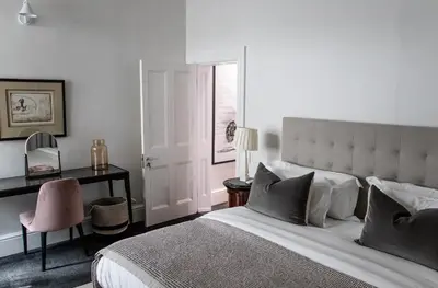 a bedroom with a bed and a desk and a chair at Heritage House in Stellenbosch