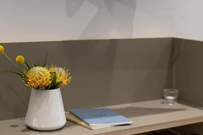 a white vase with yellow flowers and a book on a table at Heritage House in Stellenbosch