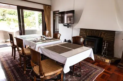 a dining room with a table and a fireplace at Cape Village Lodge in Durbanville