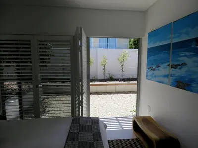 a room with a bedroom with a view of a patio at Troon Beach Cottage Hermanus in Hermanus