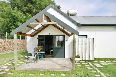 a small white house with a table and a patio at De Hoop Farm - Mountain View in Breerivier