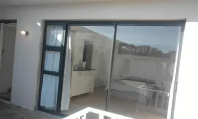 a room with a sliding glass door with a bedroom at Blouberg Beach Retreat in Bloubergstrand