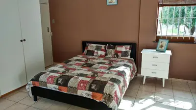a bedroom with a bed with a quilt and a dresser at Blouberg Beach Retreat in Bloubergstrand