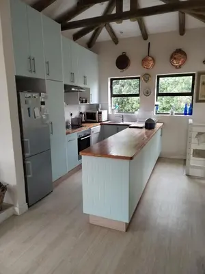 a kitchen with white cabinets and a wooden counter top at Gogo's garden apartment in Pringle Bay