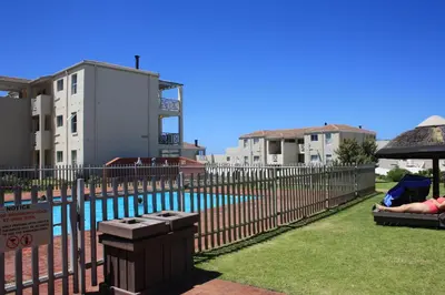 a fence next to a swimming pool with buildings at 176 hbc in Hermanus