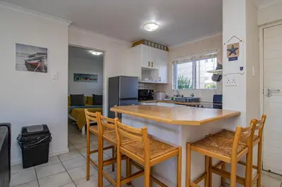 a kitchen with a counter and chairs in a room at 176 hbc in Hermanus