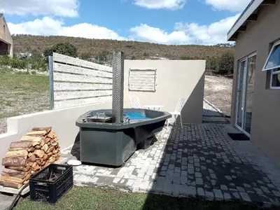 a bath tub sitting on a patio next to a house at Treyntjes Rivier Cottages in Caledon