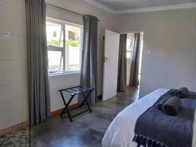a bedroom with a bed and a window at Treyntjes Rivier Cottages in Caledon