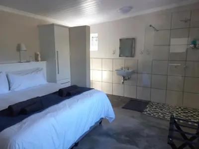a bedroom with a bed and a bathroom with a sink at Treyntjes Rivier Cottages in Caledon