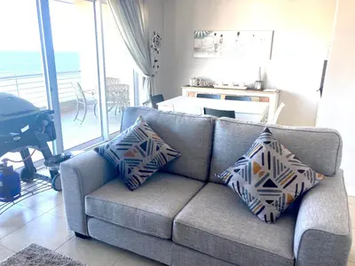 a gray couch with pillows in a living room at Portico 606 in Bloubergstrand
