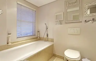 a white bathroom with a tub and a toilet at Portico 606 in Bloubergstrand