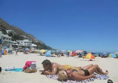 a man and a woman laying on the beach at GORDON's SHORE LUXURY APARTMENTS - Solar Powered in Gordonʼs Bay