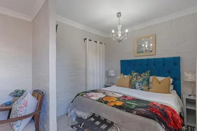 a bedroom with a large bed with a blue headboard at Petite Apartment in Bellville