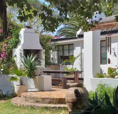 a house with a bench in front of it at Weavers' Cottage in Gordonʼs Bay