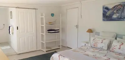 a bedroom with a bed and a white door at Weavers' Cottage in Gordonʼs Bay