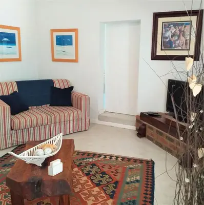 a living room with a couch and a table at Weavers' Cottage in Gordonʼs Bay