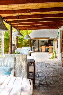 a patio with a table and chairs under a wooden pergola at Khashamongo B & B in Somerset West
