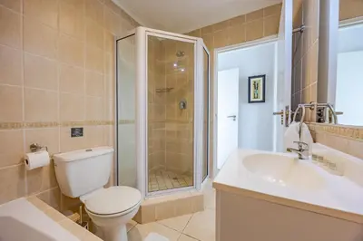 a bathroom with a shower and a toilet and a sink at Luxury Ocean View Beachfront 2 bed apartment -206 The Waves, Blouberg, Cape Town in Bloubergstrand