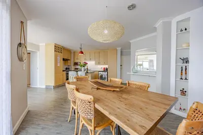 a kitchen and dining room with a wooden table and chairs at Luxury Ocean View Beachfront 2 bed apartment -206 The Waves, Blouberg, Cape Town in Bloubergstrand