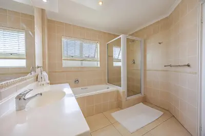 a bathroom with a sink and a shower and a tub at Luxury Ocean View Beachfront 2 bed apartment -206 The Waves, Blouberg, Cape Town in Bloubergstrand
