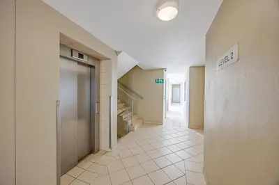 a hallway with a door and stairs in a building at Luxury Ocean View Beachfront 2 bed apartment -206 The Waves, Blouberg, Cape Town in Bloubergstrand