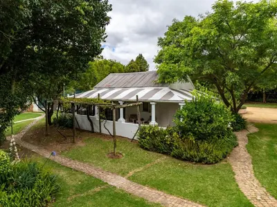 a white house with a roof on a yard at Caledon Grace Guesthouse in Caledon