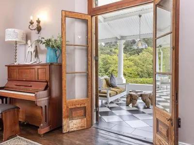 an open door to a living room with a piano at Caledon Grace Guesthouse in Caledon